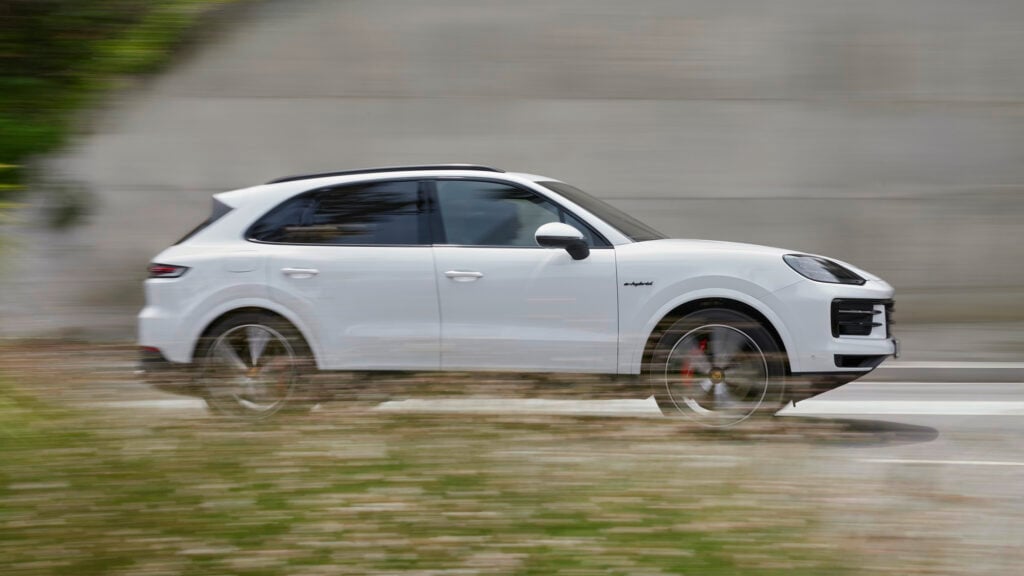 En vit Porsche Cayenne kör längs en väg. (AI text)