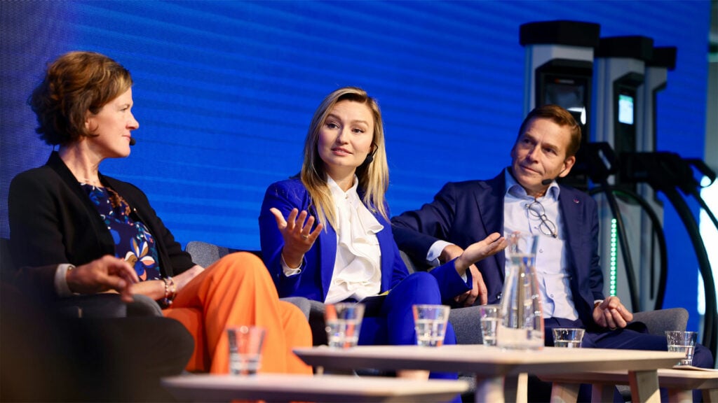 En grupp personer sittande på scenen vid en konferens. (AI text)