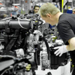 En biltillverkare monterar en motor i en fabrik. (AI text)