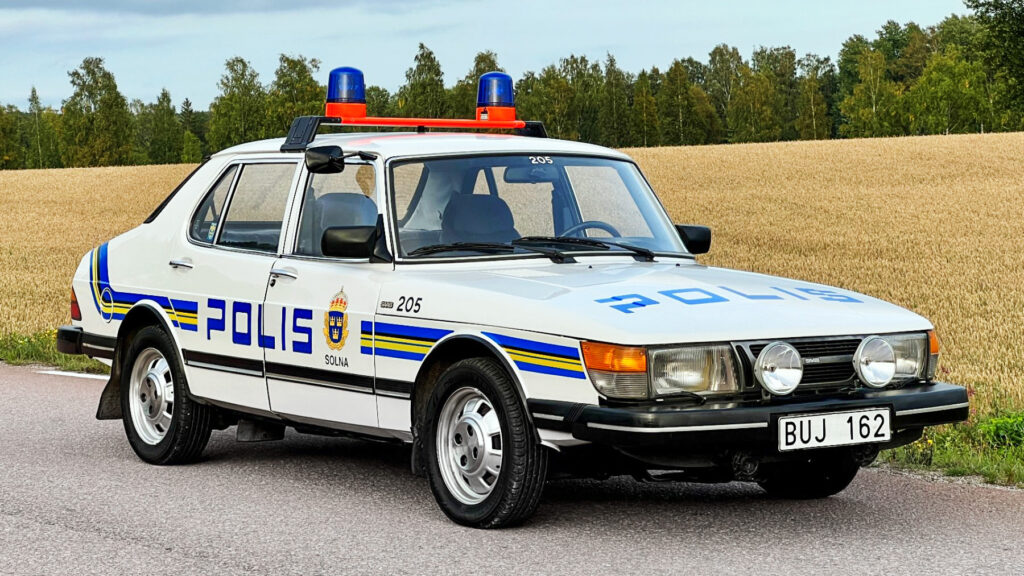 En polisbil kör längs en landsväg. (AI text)