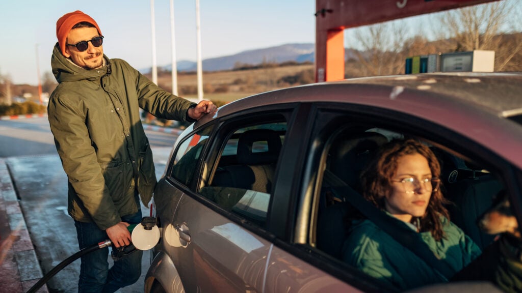 En man och kvinna tankar sin bil vid en bensinstation. (AI text)