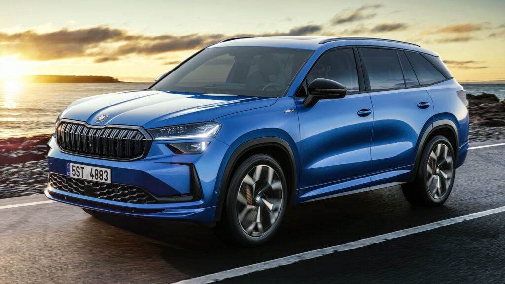 En blå SUV kör längs en väg med solnedgång bakom den. (AI text)