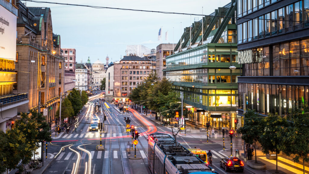 En stadsgata med bilar och folk. (AI text)