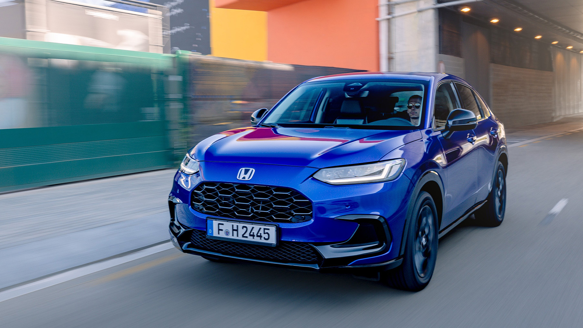 En blå SUV kör nerför en stadsgata. (AI text)