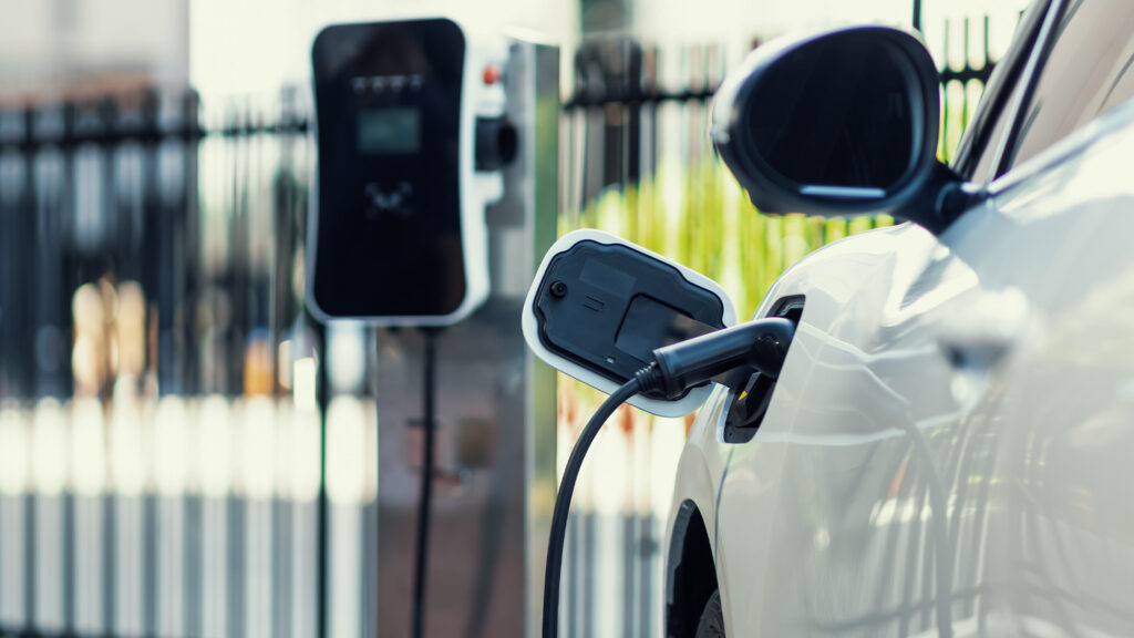 En vit bil är uppkopplad till en elbilstation för laddning. (AI text)