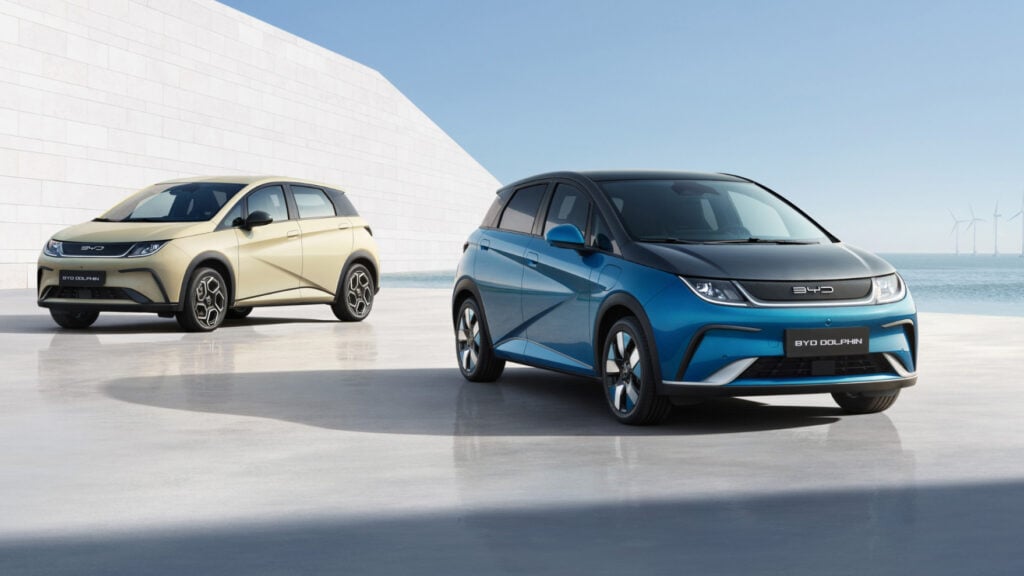 Två elbilar parkerade framför en byggnad. (AI text)