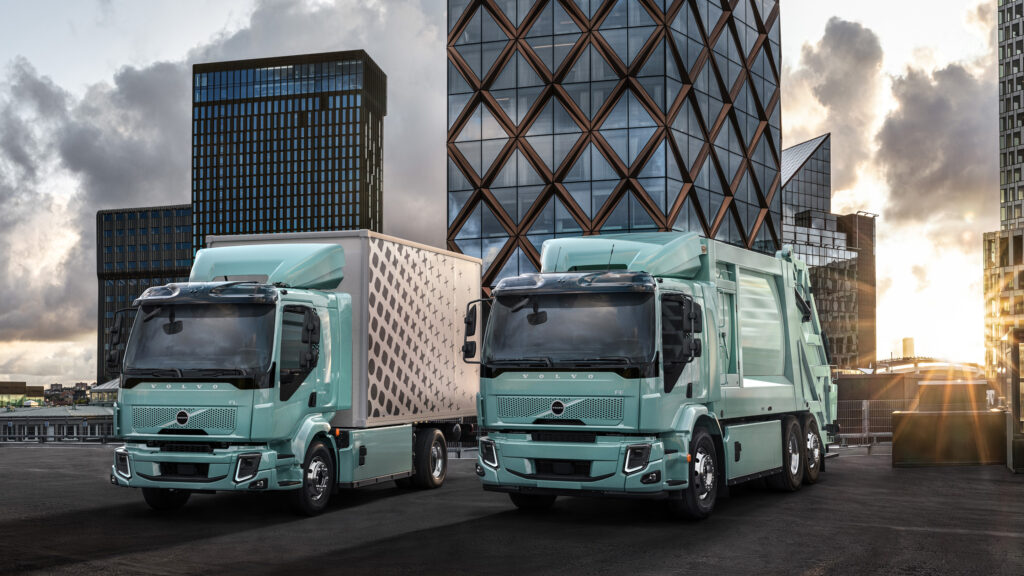 Två lastbilar parkerade framför ett byggnad. (AI text)