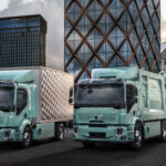 Två lastbilar parkerade framför ett byggnad. (AI text)