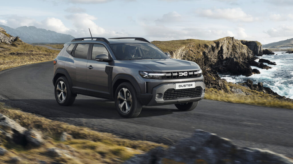 En grå självstyrande fordon kör längs en väg vid havet. (AI text)