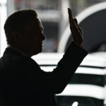 En man vinkar till publiken vid lanseringen av Audi A6. (AI text)