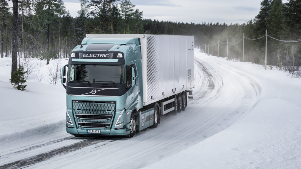 En lastbil kör nedför en snöig väg. (AI text)