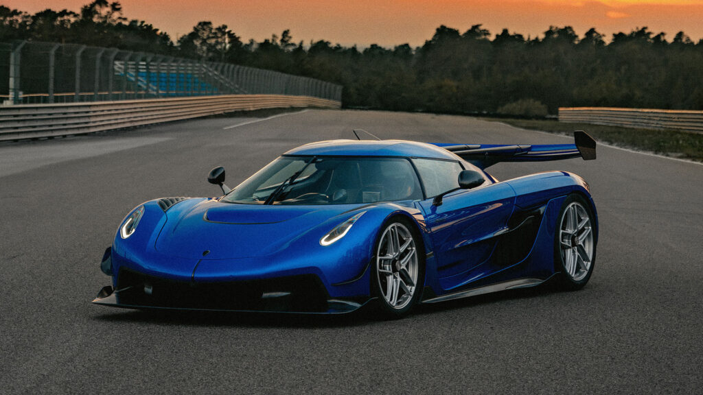 En blå sportbil kör nedför en racerbana vid solnedgången. (AI text)