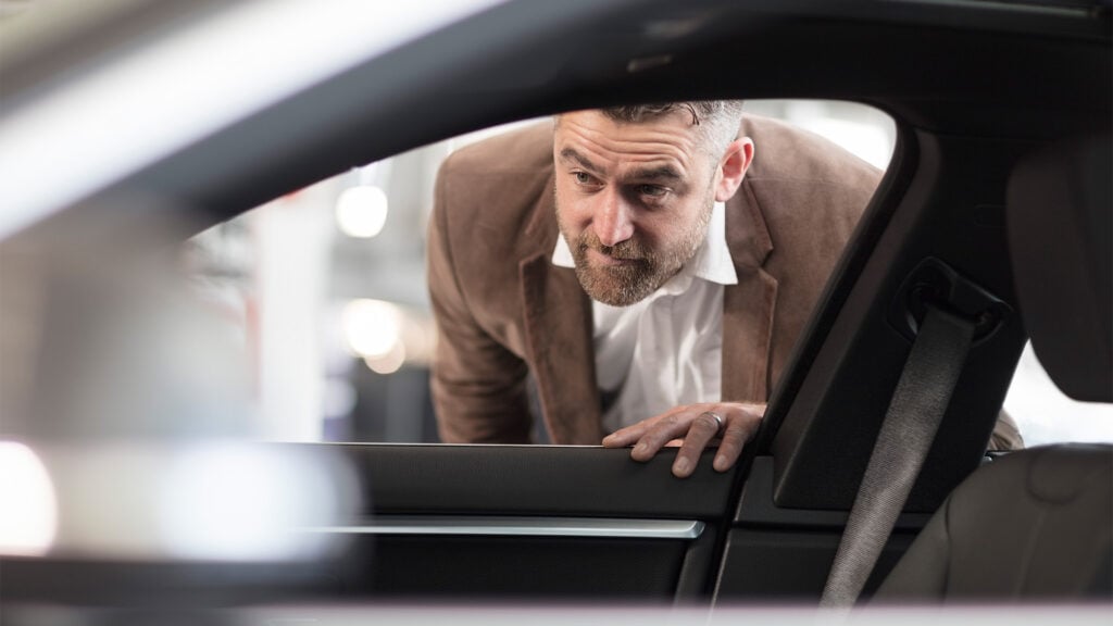 En man tittar ut genom fönstret i en bil. (AI text)