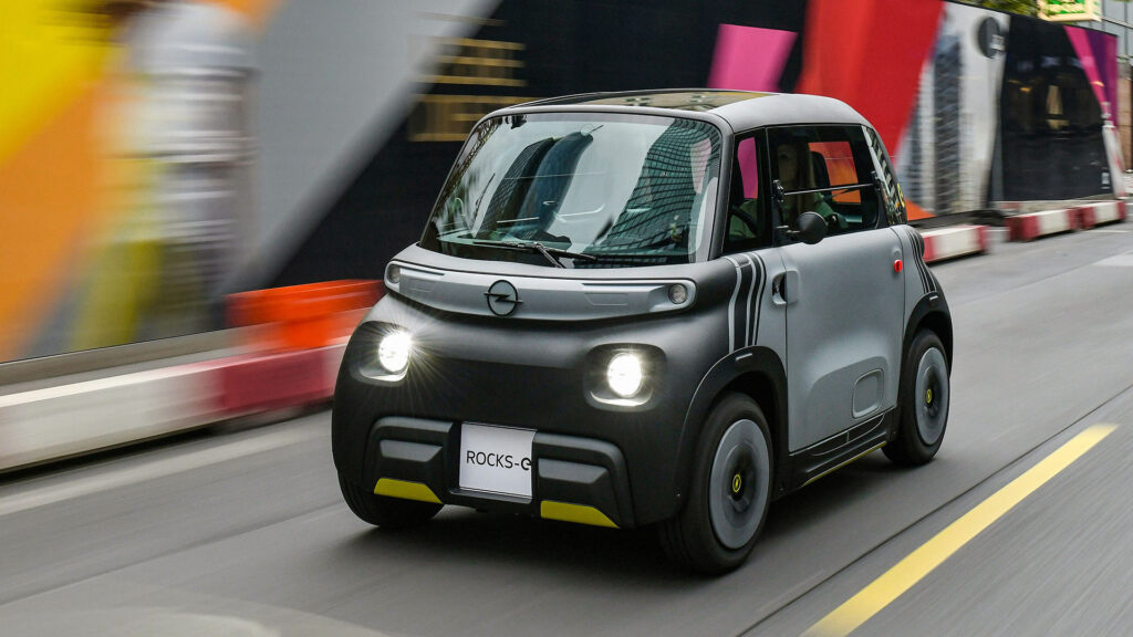 En liten elbil kör nerför en stadsgata. (AI text)