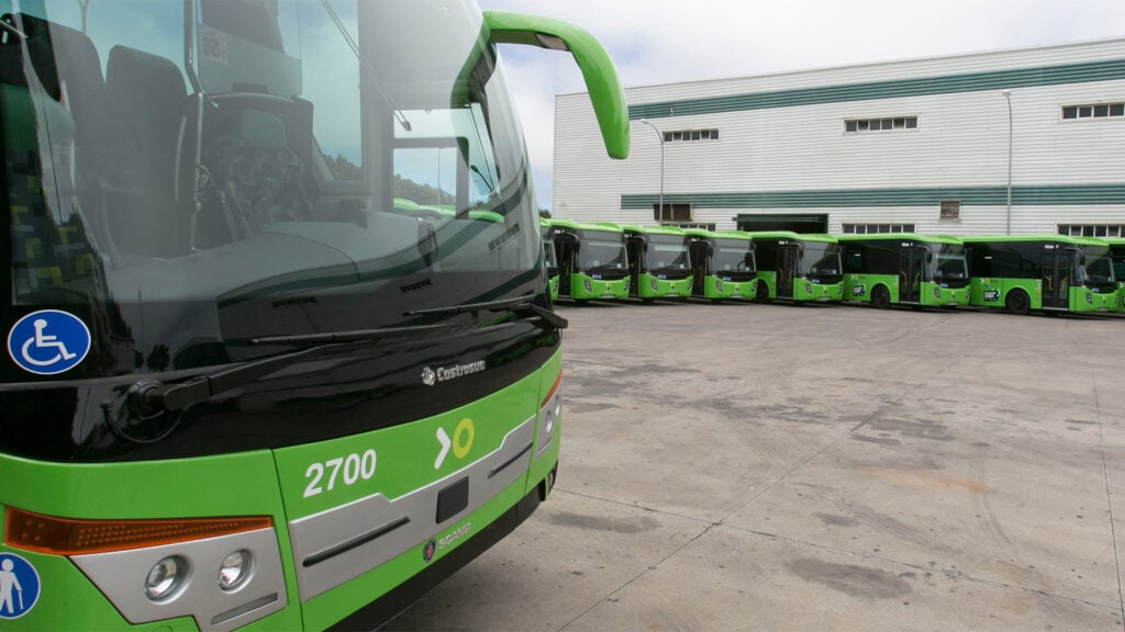 En grön buss parkerad framför ett byggnad. (AI text)