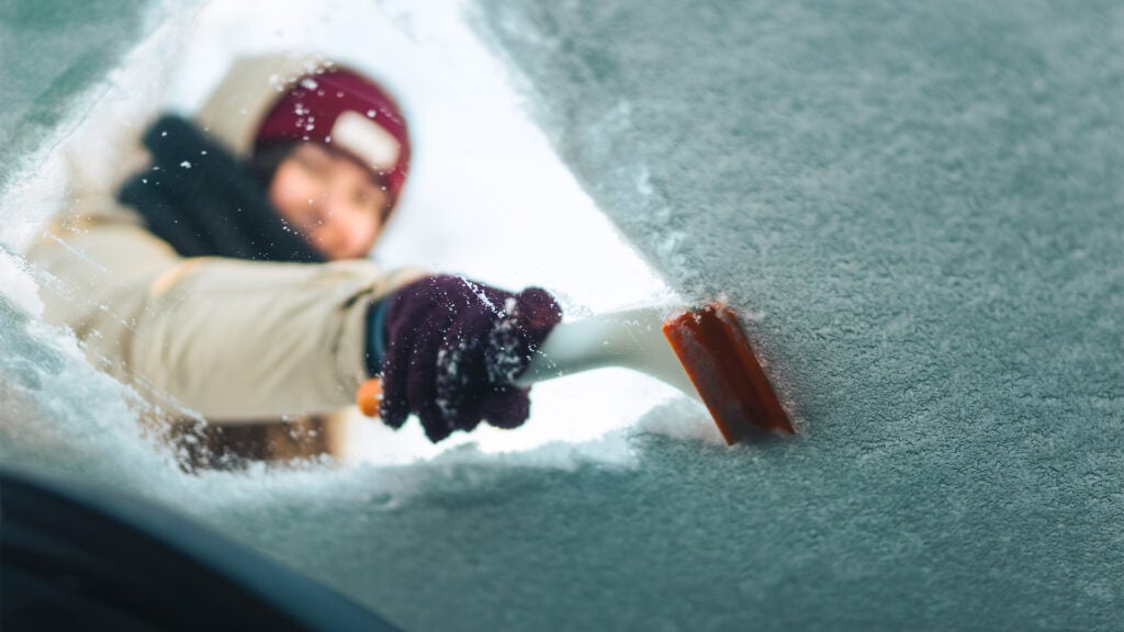 En kvinna rengör rutan på sin bil. (AI text)