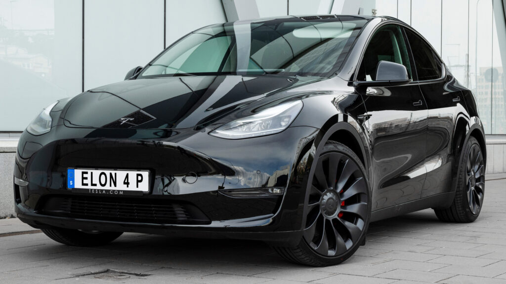 En Tesla Model Y parkerad framför ett byggnad. (AI text)