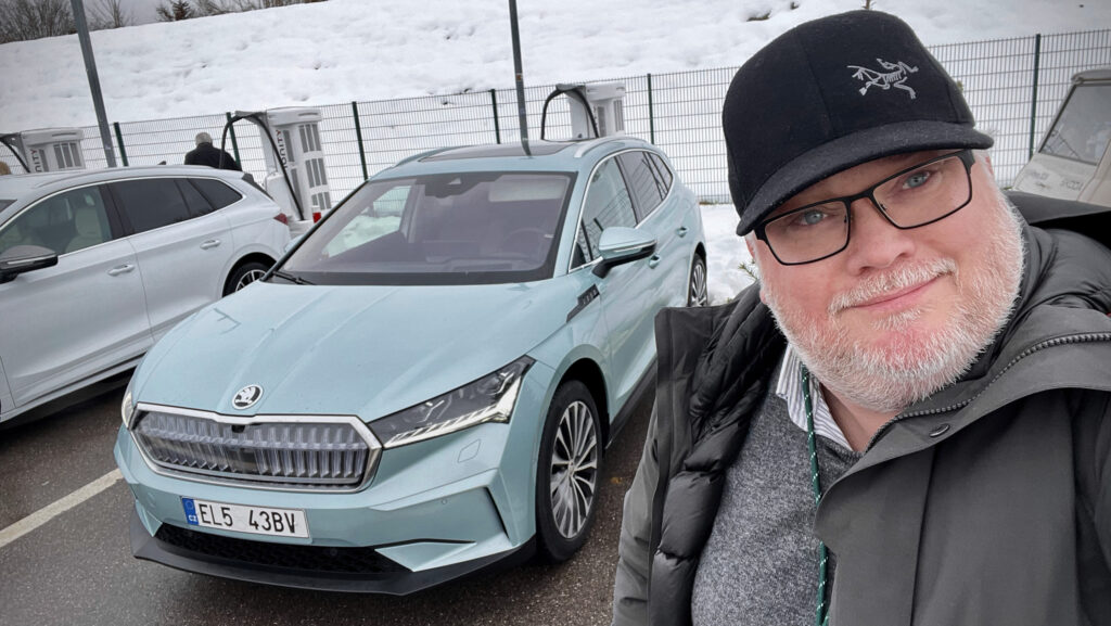 En man i hatt tar en selfie tillsammans med en bil. (AI text)