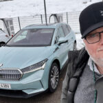 En man i hatt tar en selfie tillsammans med en bil. (AI text)