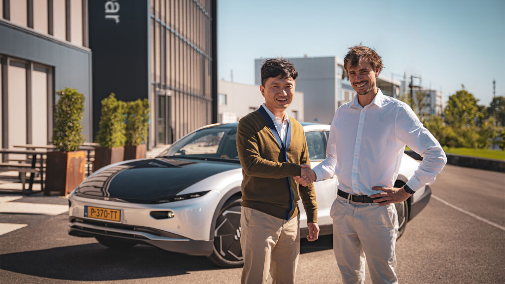 Två män står bredvid en bil. (AI text)