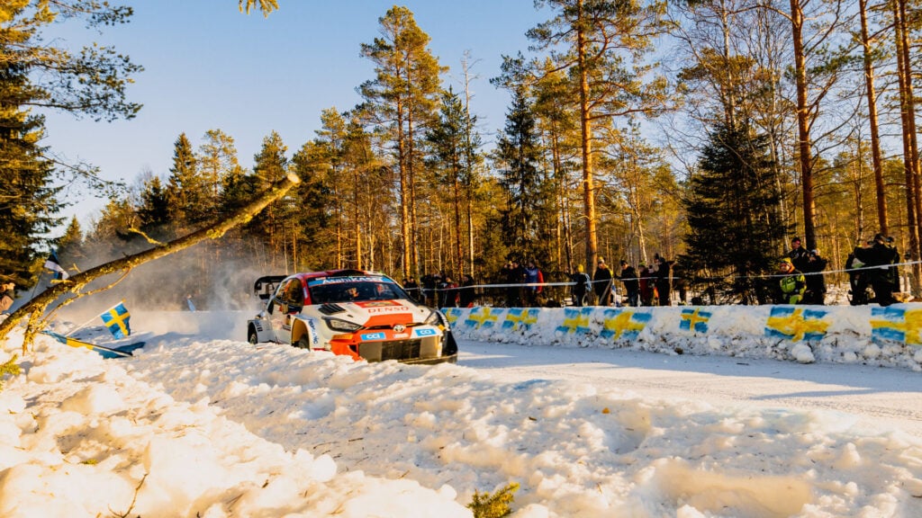 En rallybil kör nerför en snötäckt väg. (AI text)
