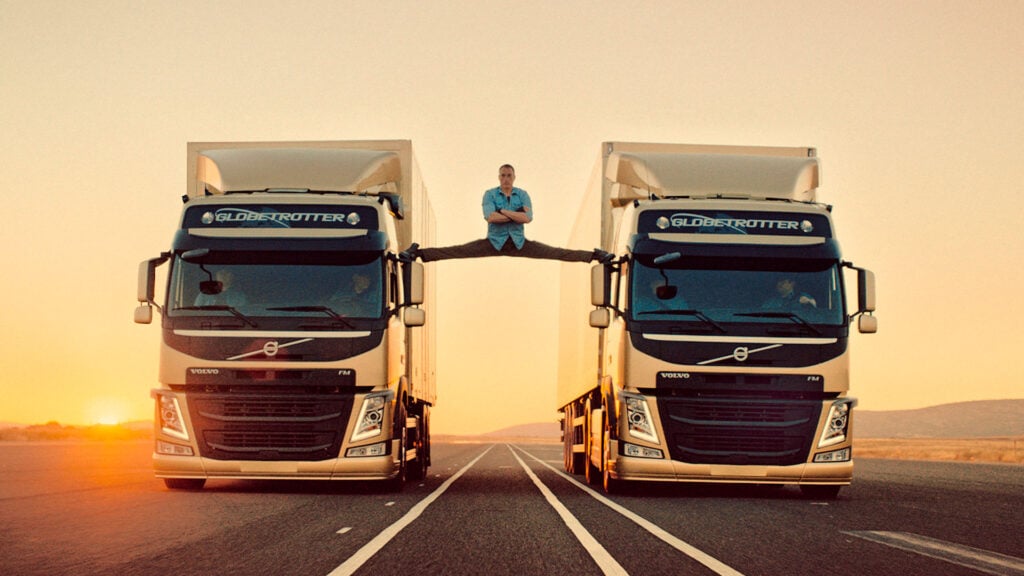 En man står på toppen av två stora lastbilar. (AI text)