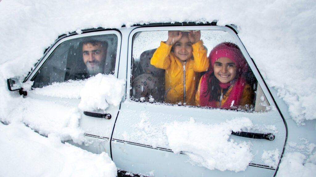 En familj sitter i en bil täckt av snö. (AI text)