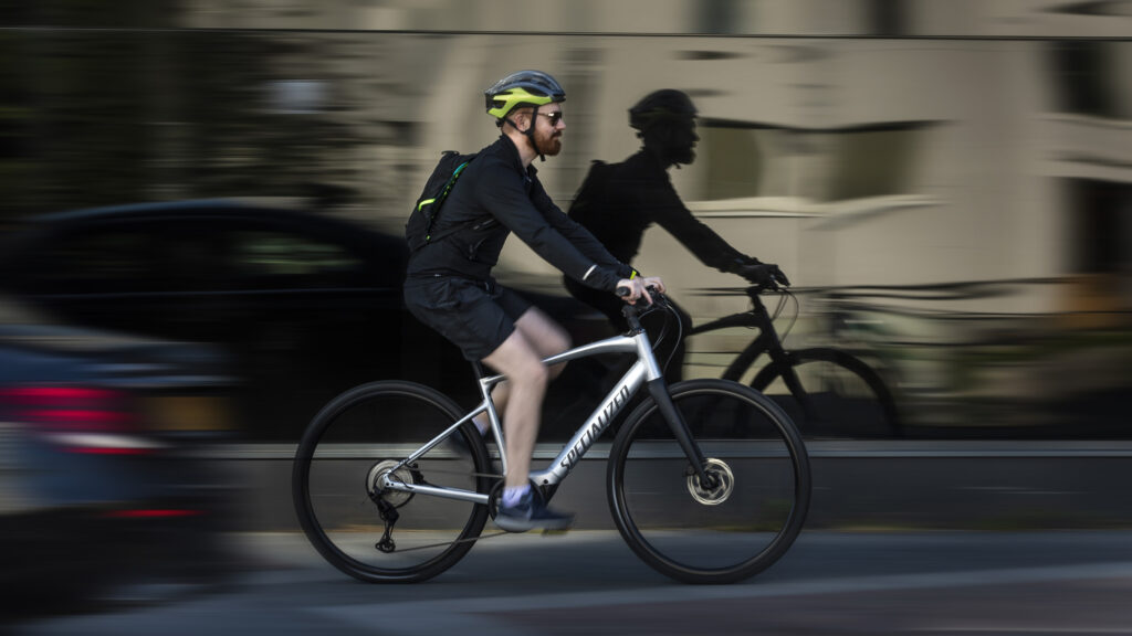 En man cyklar på en stadsgata. (AI text)