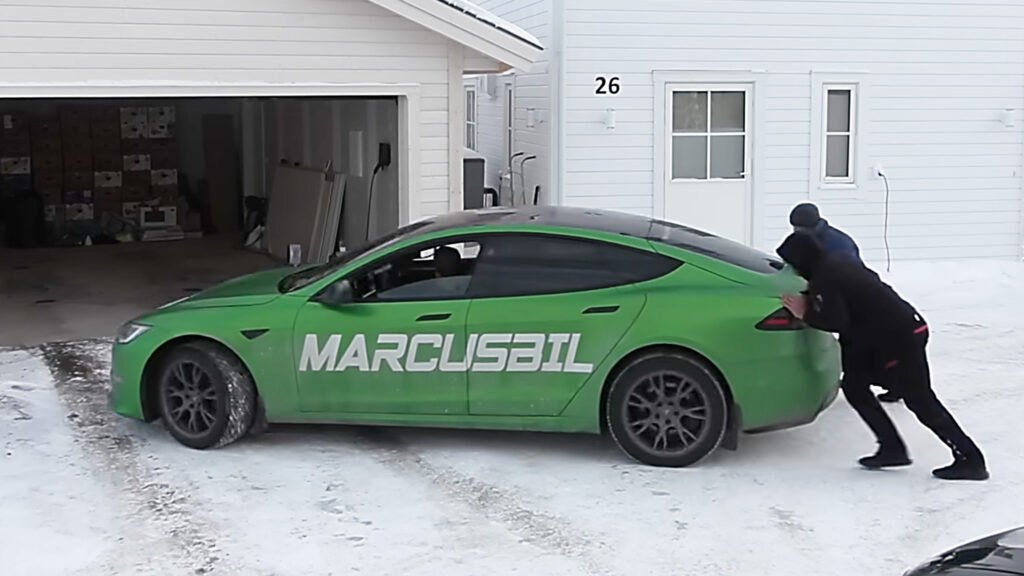 En grön Tesla Model S parkerad i ett garageuppfart. (AI text)