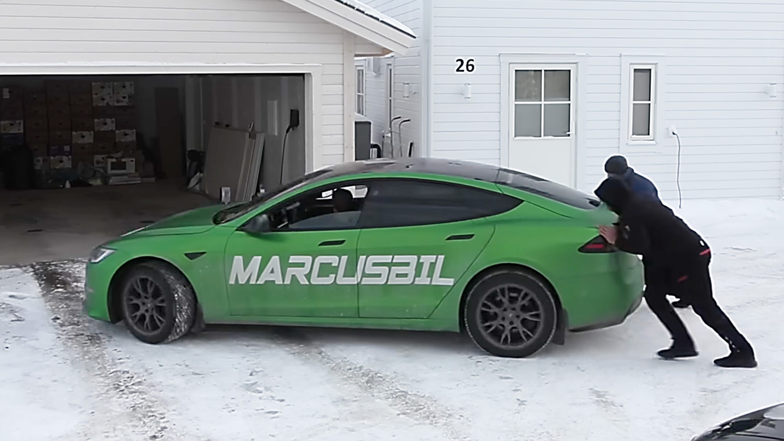 En grön Tesla Model S parkerad i ett garageuppfart. (AI text)