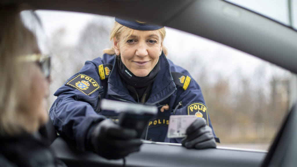 En polis kontrollerar föraren licens. (AI text)
