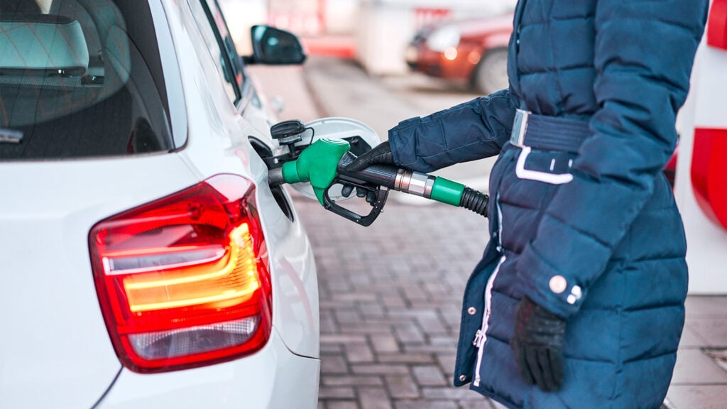 En kvinna fyller på bränsle i sin bil vid en bensinstation. (AI text)