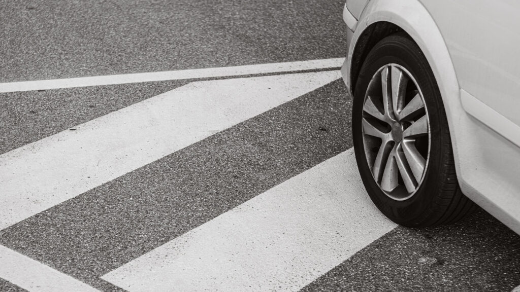 En vit bil parkerad på en övergångsställe. (AI text)