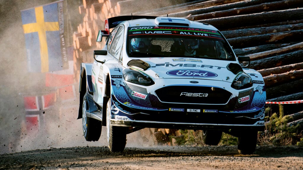 En rallybil kör genom en skog. (AI text)