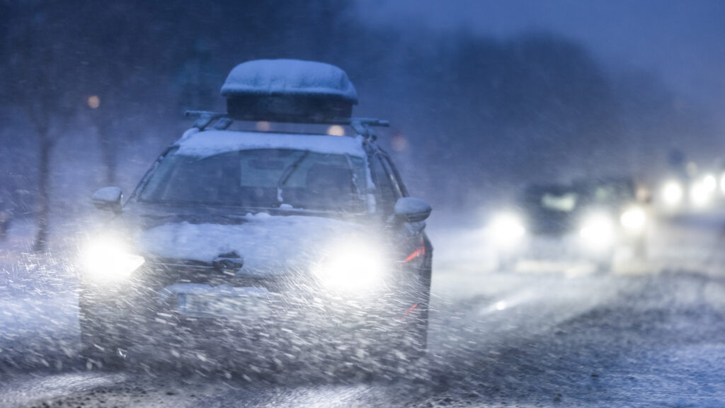 En bil kör framåt på en snöig väg. (AI text)