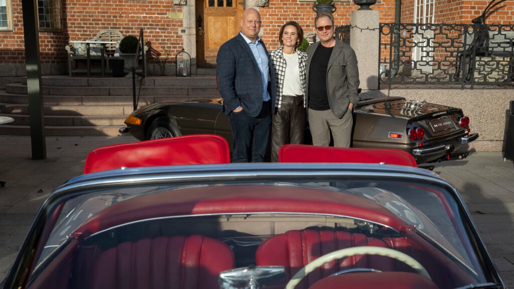 En man och en kvinna står bredvid en klassisk bil. (AI text)