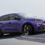 En lila SUV kör nerför en väg. (AI text)