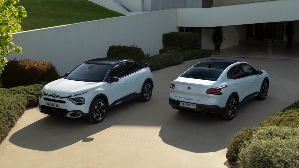 Två vita SUV:er parkerade framför ett modernt hus. (AI text)