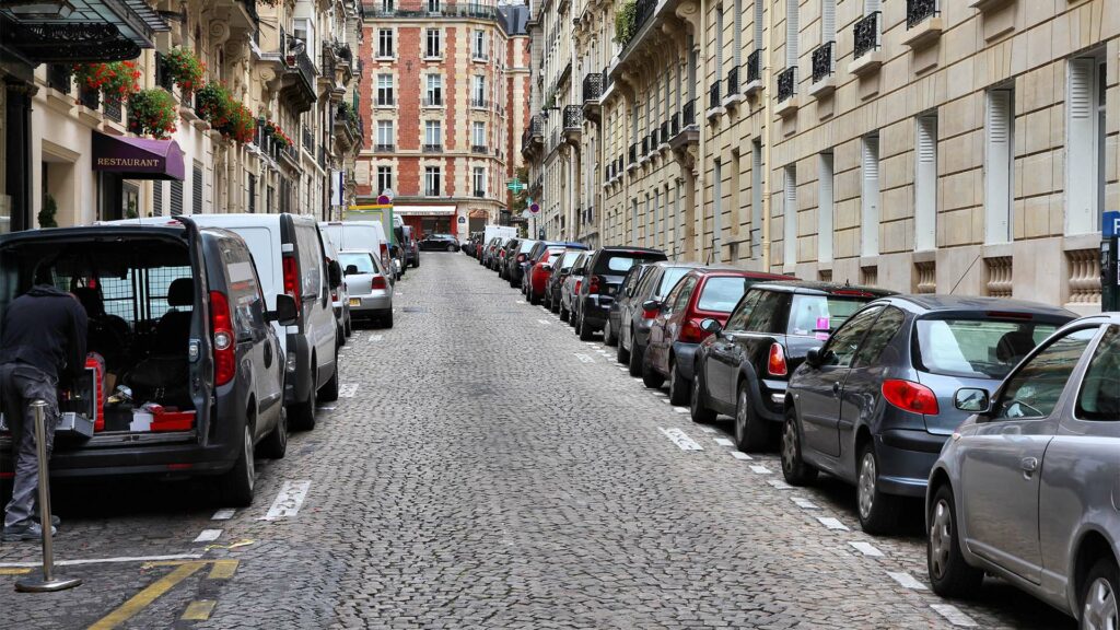 En gata i Paris med parkerade bilar. (AI text)
