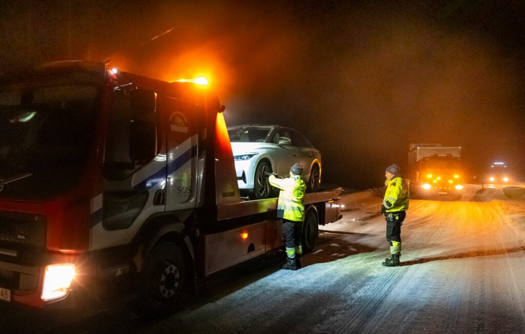 En biltowtruck tärper en bil på en snöig väg. (AI text)