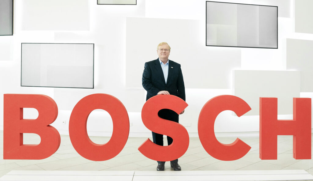 En man står framför ett Bosch-skylte. (AI text)