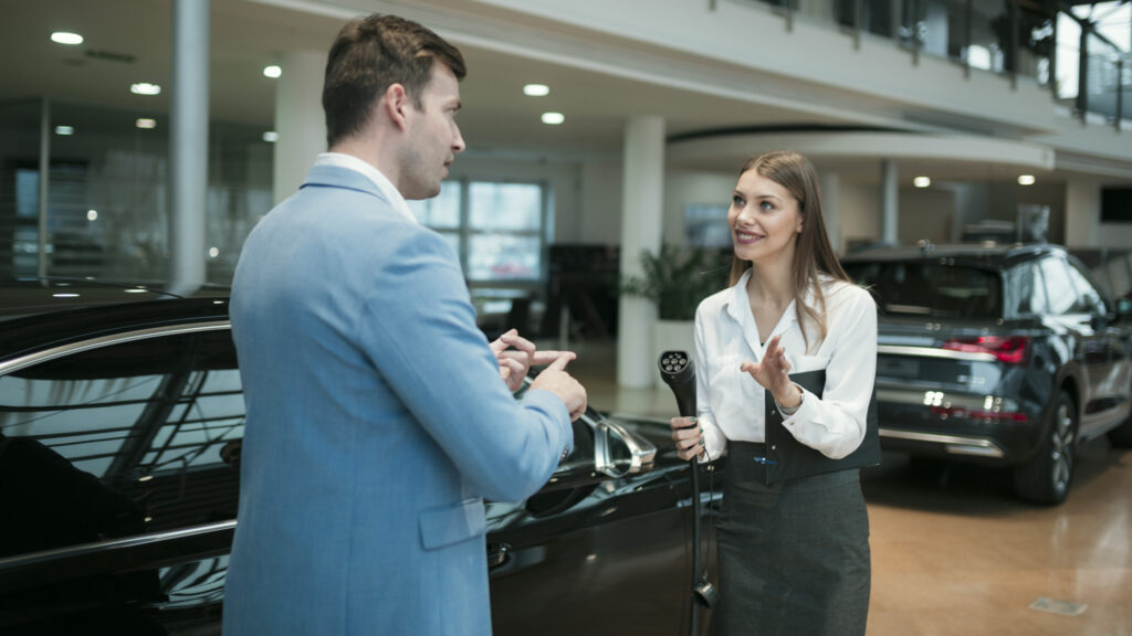 En affärsman och en kvinna pratar om en bil i en showrum. (AI text)