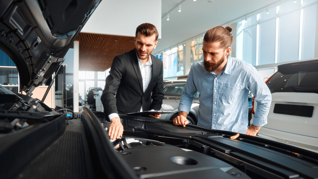 Två män tittar på en bil i en showrum. (AI text)