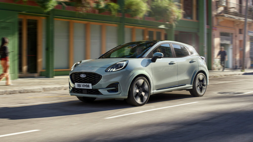 En grön Ford Kuga kör nerför en stadsgata. (AI text)