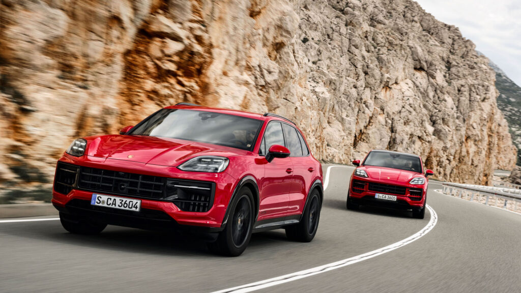 Två röda Porsche Cayenne kör nedför en bergsväg. (AI text)