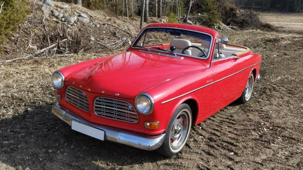 En röd Volvo C30 cabriolet parkerad på en grusväg. (AI text)