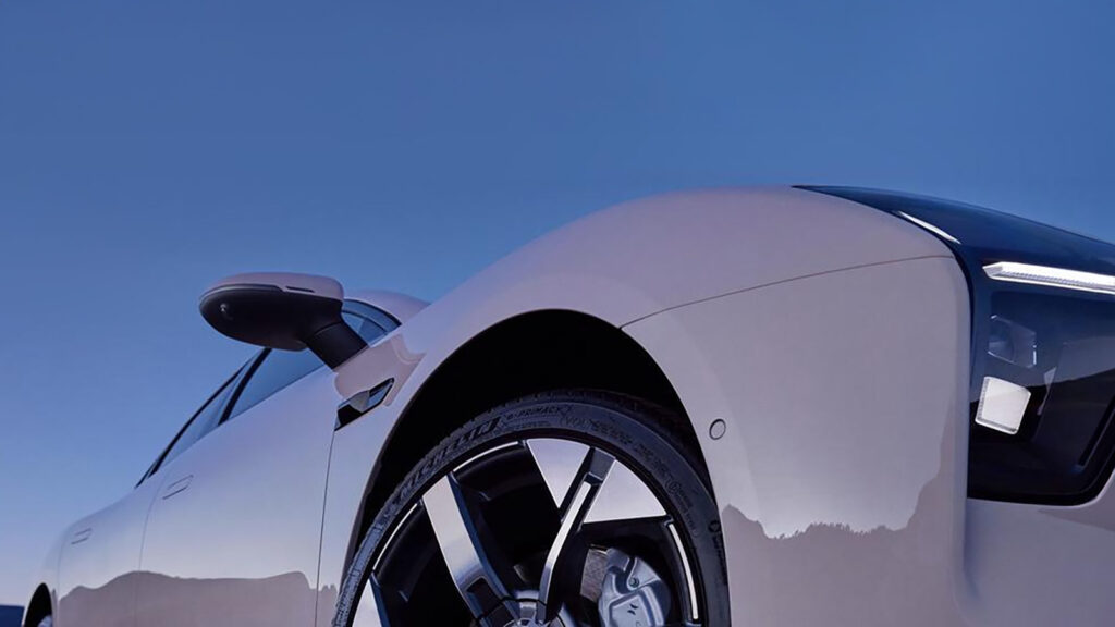 En vit bil parkerad på en backe. (AI text)