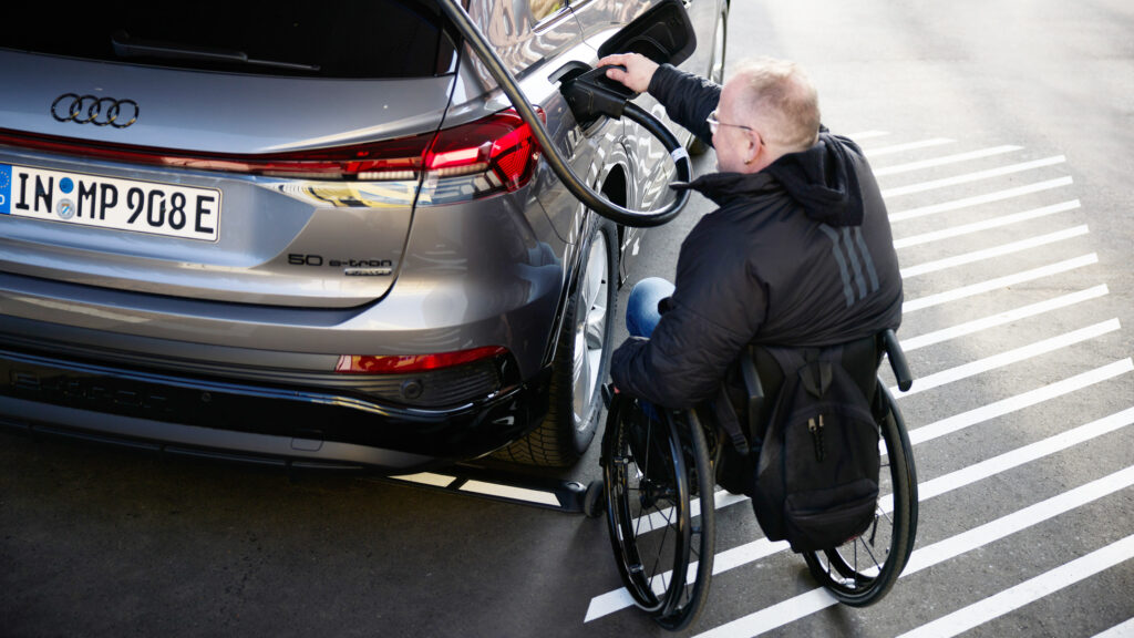 En man i rullstol lastar sin hjulupphängning på en bil. (AI text)