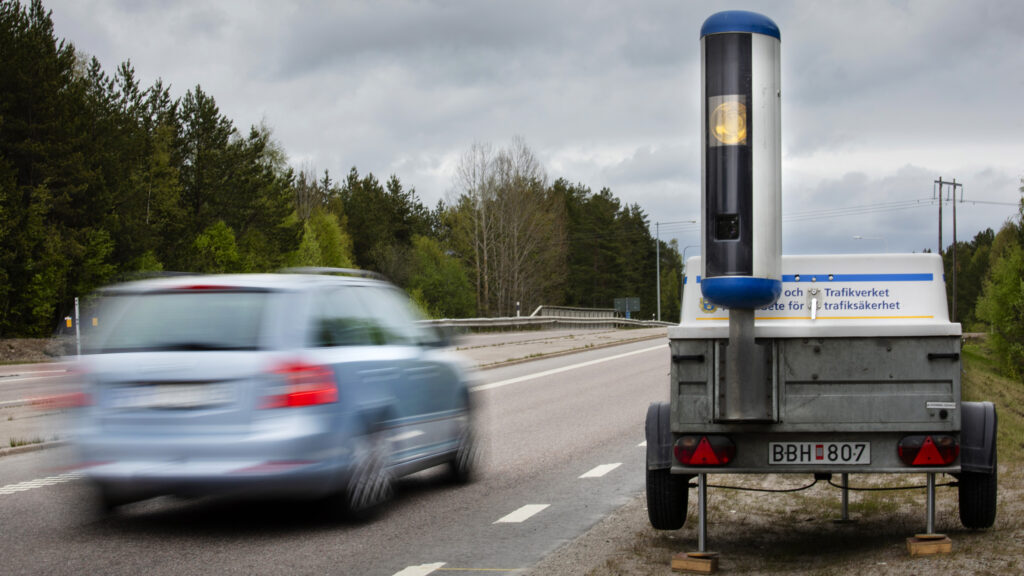 En bil kör nedför en väg med en släp kopplat till den. (AI text)