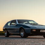 En klassisk bil parkerad vid en väg i landsbygden (AI text)